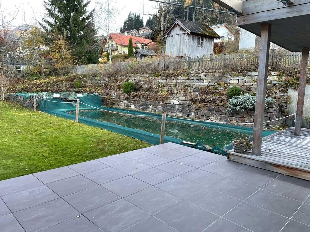 Biopool in de herfst met beschermnet, terras en natuurstenen muur