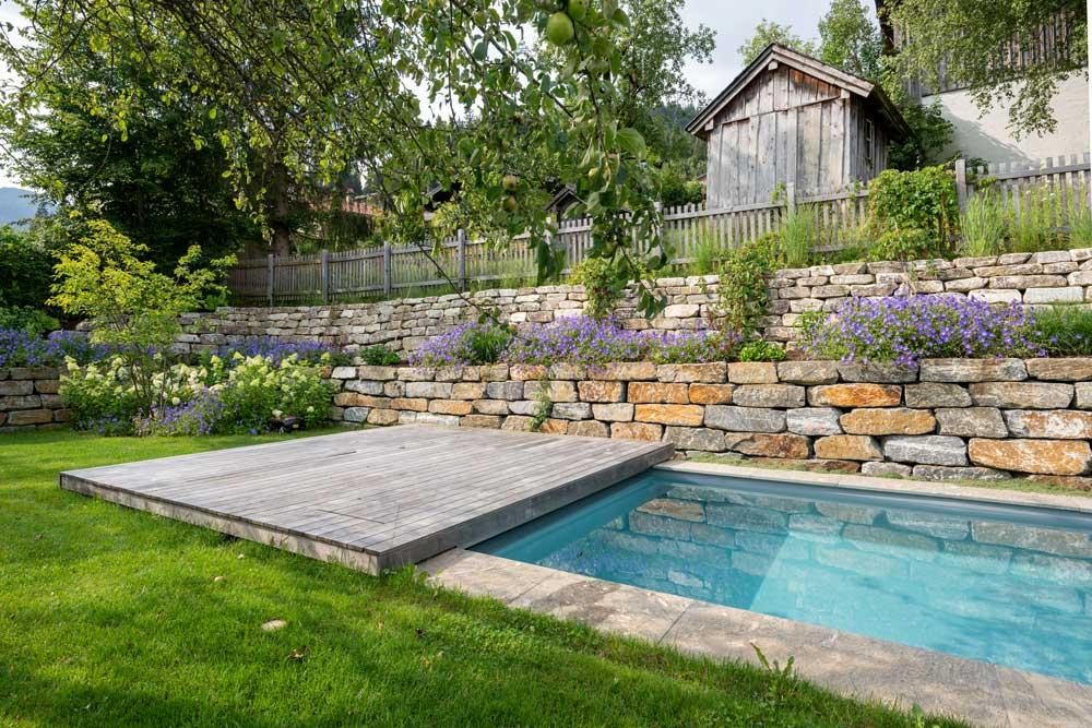 Biopool met houten terras, natuurstenen muur en bloeiende beplanting