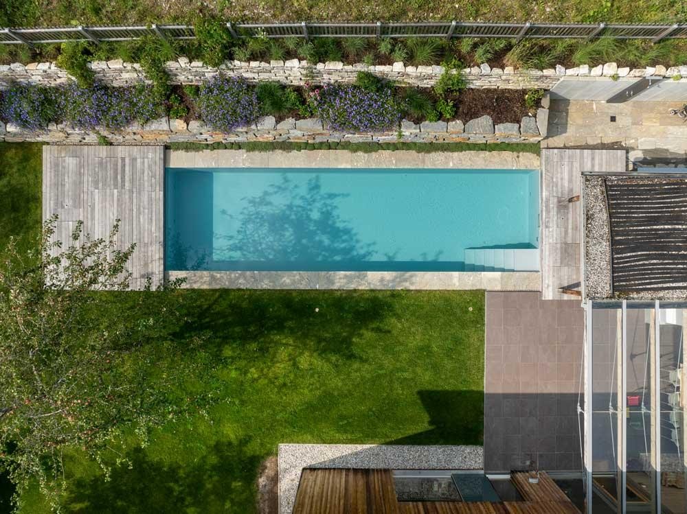 Biopool van bovenaf met terras, gazon en natuurstenen muur
