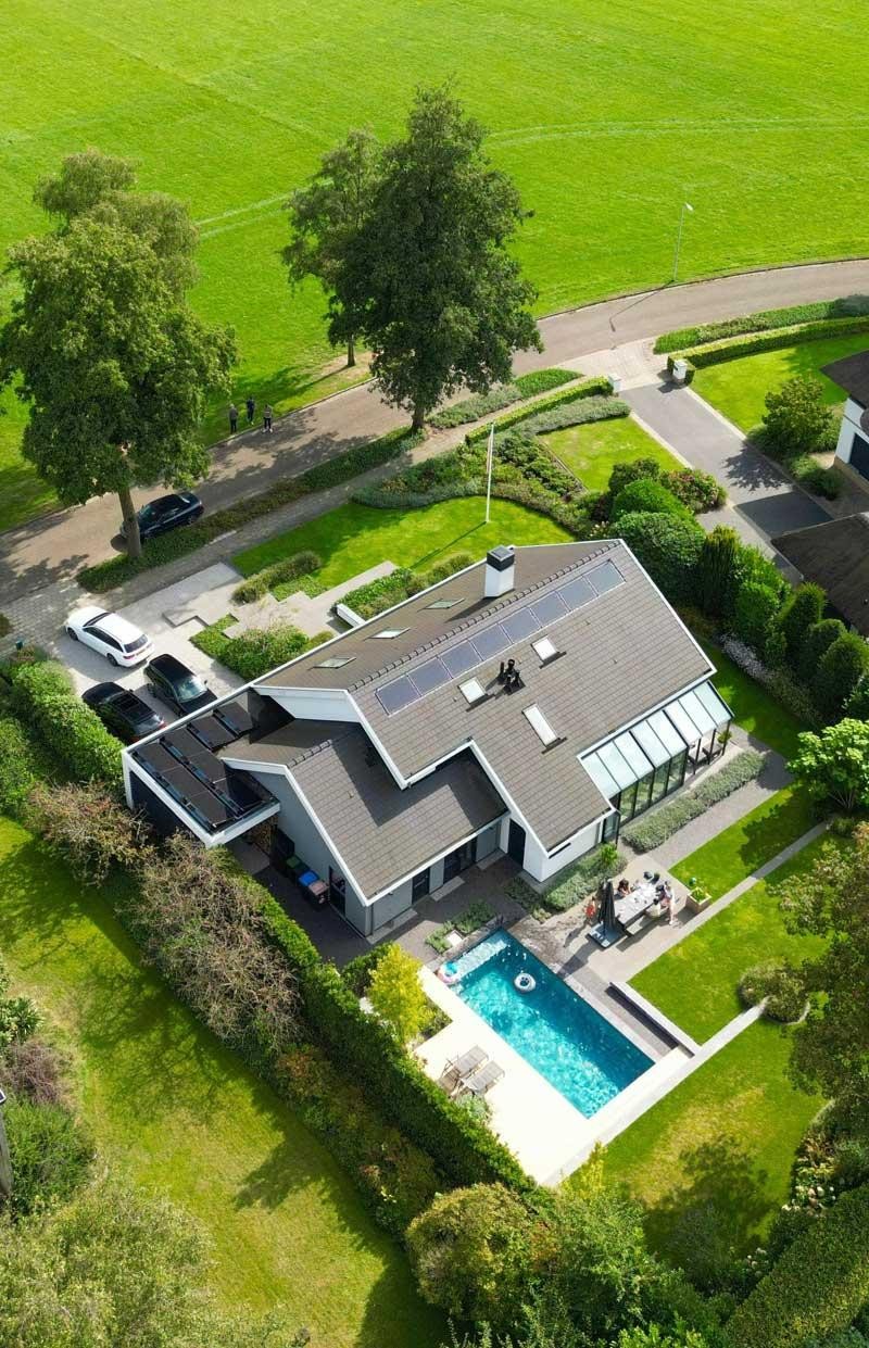 Luchtfoto van designpool en vrijstaande woning in verzorgde tuin