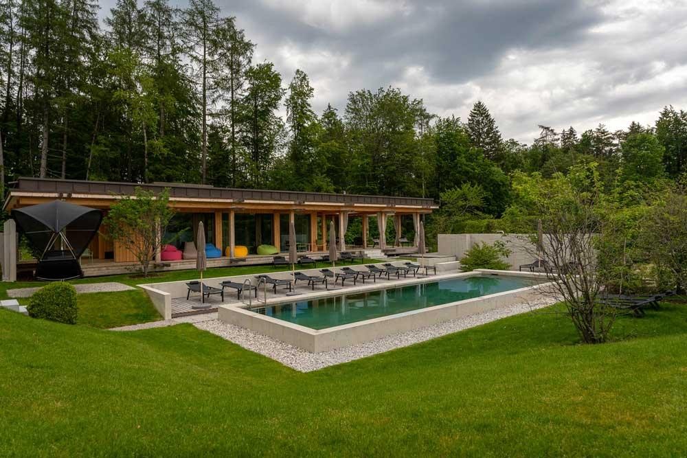 Grote biopool in de hoteltuin met ligstoelen en moderne architectuur