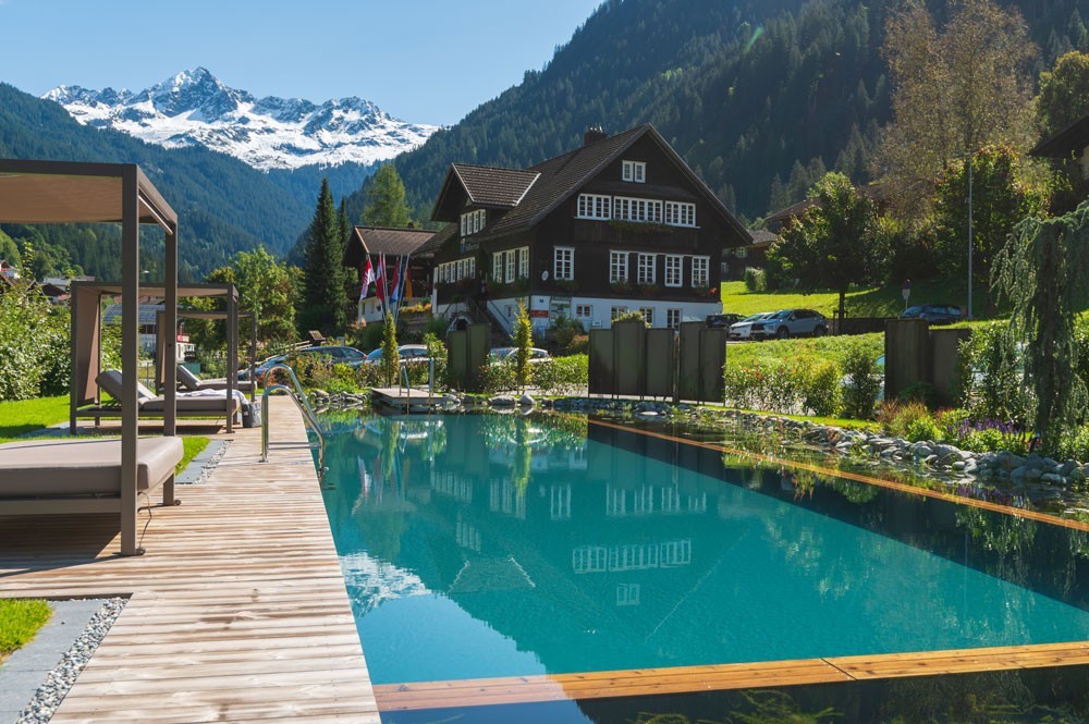 Hotelzwembad met uitzicht op de bergen voor een Alpenhotel en houten terras