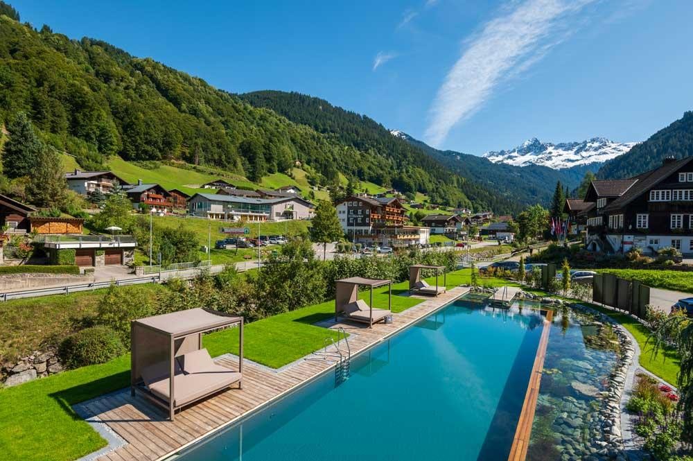 Luchtfoto van een hotelzwembad in een Alpendorp met berglandschap