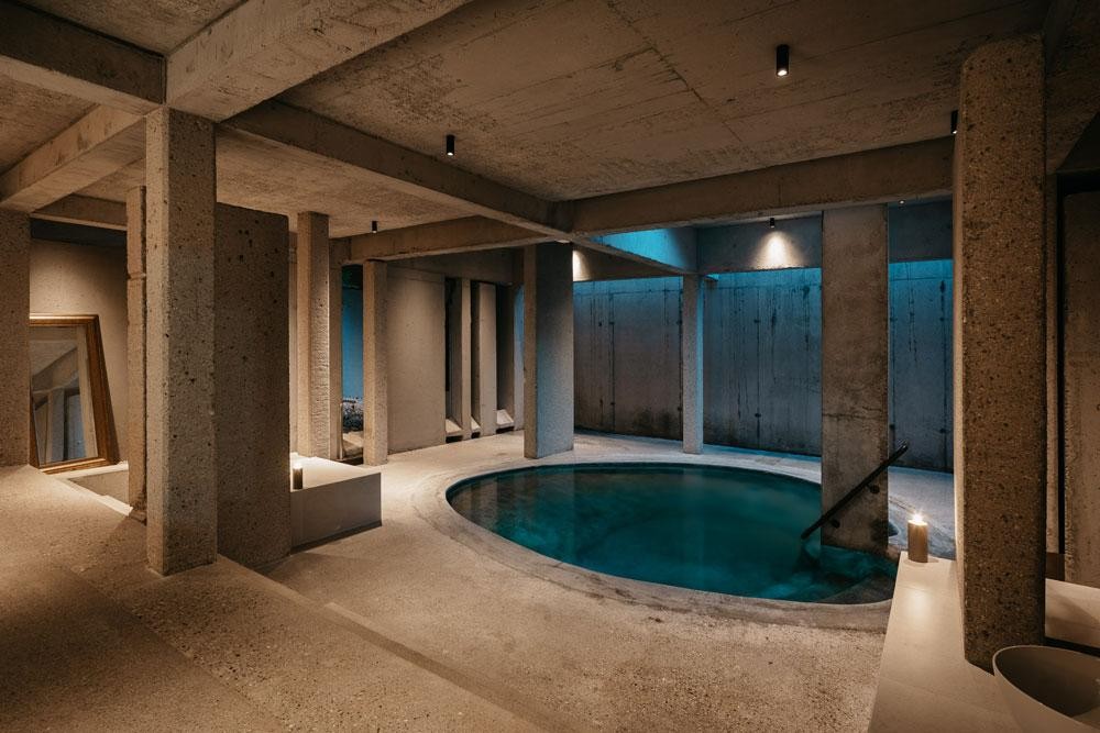 Rond binnenzwembad met betonarchitectuur en sfeervolle verlichting