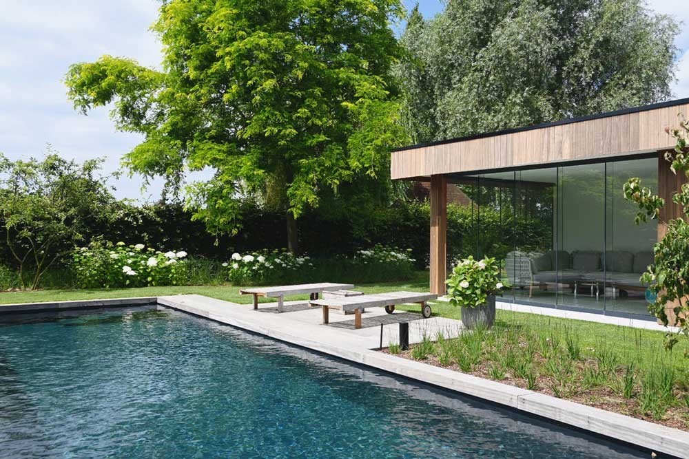 Biotop Living Pool met modern poolhouse in een verzorgde tuin met terras en natuurzwembad