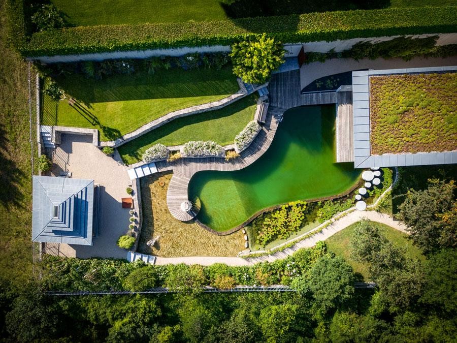 Biotop natuurlijk zwembad van boven met houten dek groendak en tuin