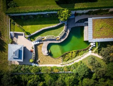 Biotop natuurlijk zwembad van boven met houten dek groendak en tuin