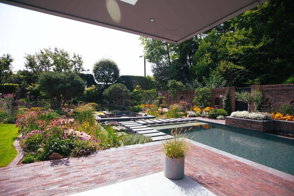 Natuurlijk zwembad met terras waterlelies en natuurlijke beplanting