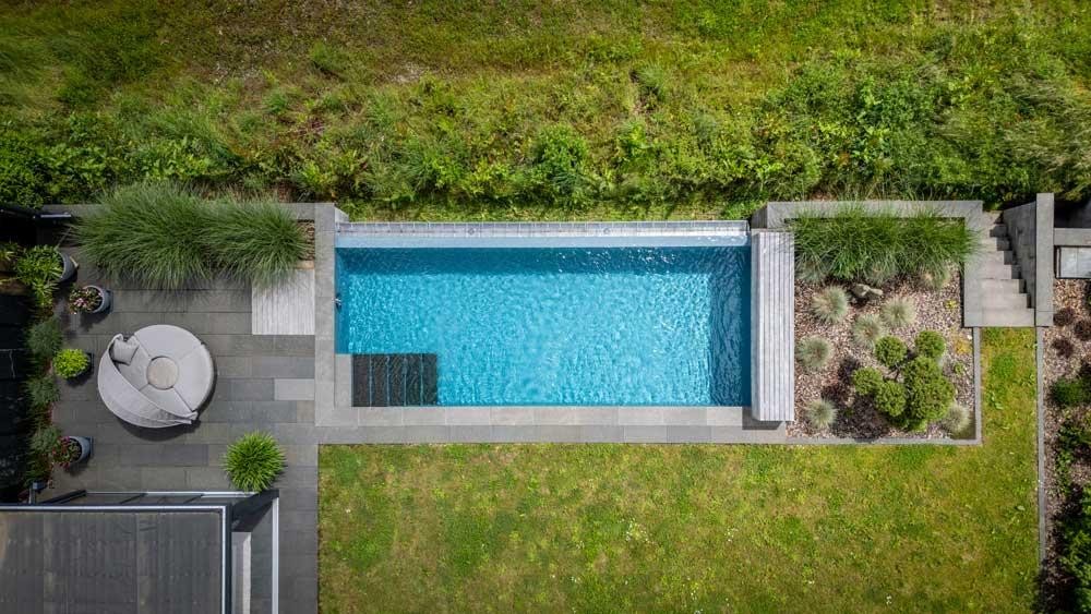 Luchtfoto van een natuurzwembad in een moderne hellingtuin