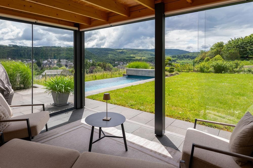 Uitzicht vanuit de woonruimte op natuurzwembad en weids landschap