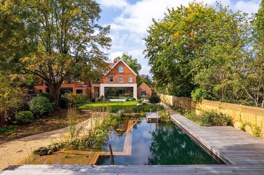 Natuurzwembad met houten terras en tuinhuis in natuurlijke tuin