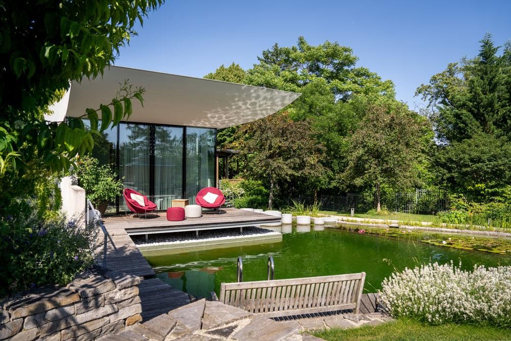 Biotop zwemvijver bij modern terras met houten dek en zithoek