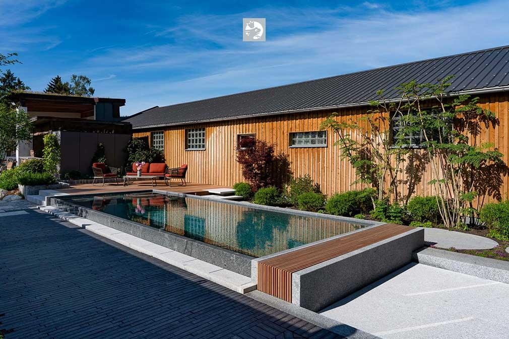 Bekroond natuurzwembad met houten huis en moderne tuininrichting