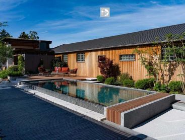Bekroond natuurzwembad met houten huis en moderne tuininrichting