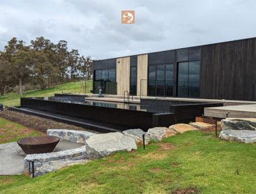 Een uitzicht op het natuurlijke zwembad en terras van een modern huis