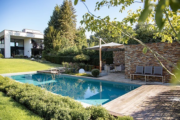 Een huis met een natuurlijk zwembad en een terras in moderne stijl