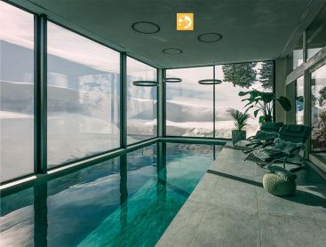 Indoor Living Pool met bergzicht en ligstoelen in wellnessruimte