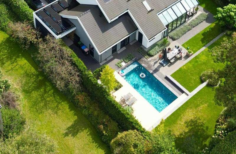 Luchtfoto van een designzwembad en een eengezinswoning in een goed onderhouden tuin