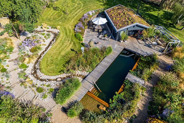 Luchtfoto van een huis met groen dak en zwemvijver
