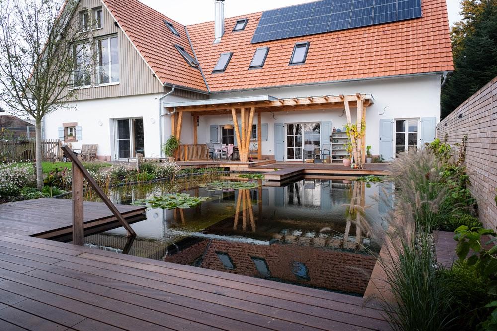 Natuurlijke zwemvijver met houten terras modern huis en zonnedak