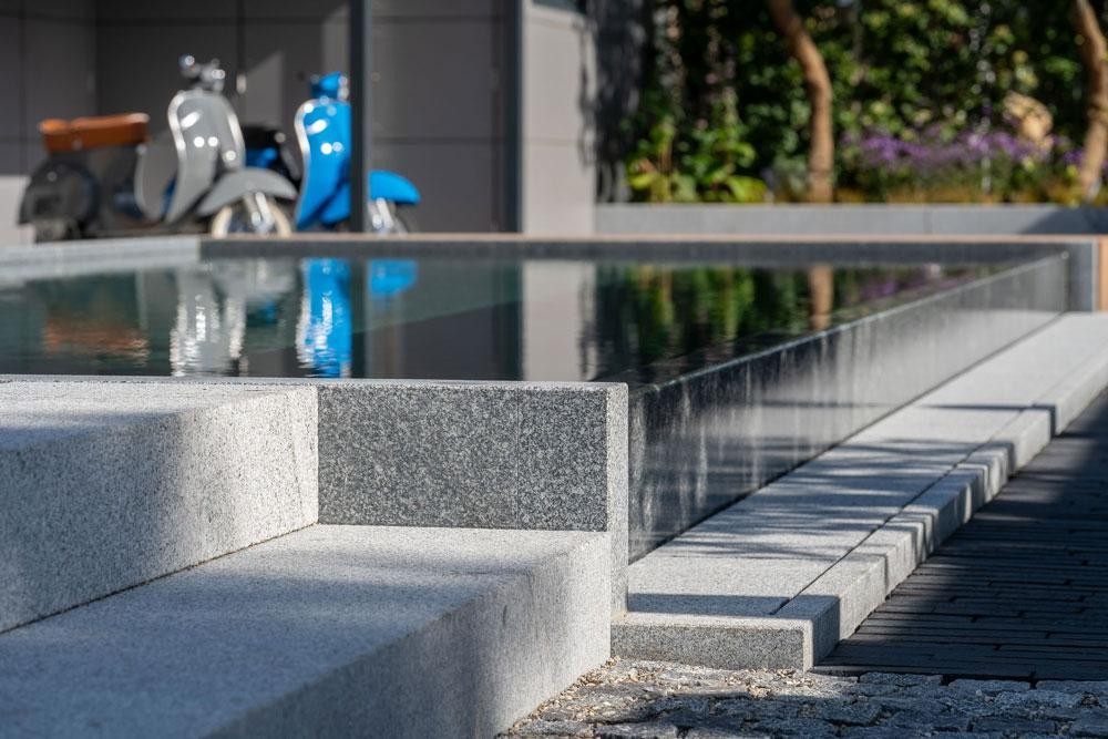 Detailopname van een natuurzwembad met Kusser granietrand en trappen
