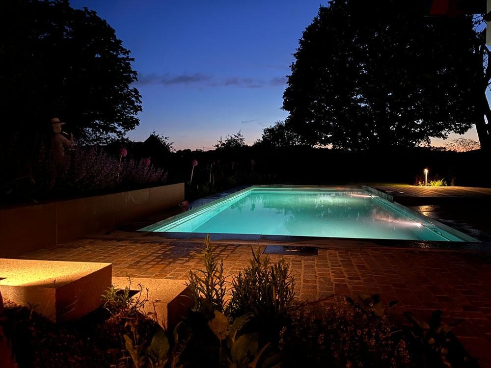 Verlichte natuurpool in de avond met tuinsfeer