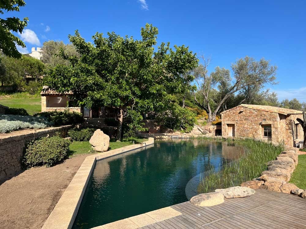 Zwemvijver met houten dek en stenen huis in mediterrane omgeving