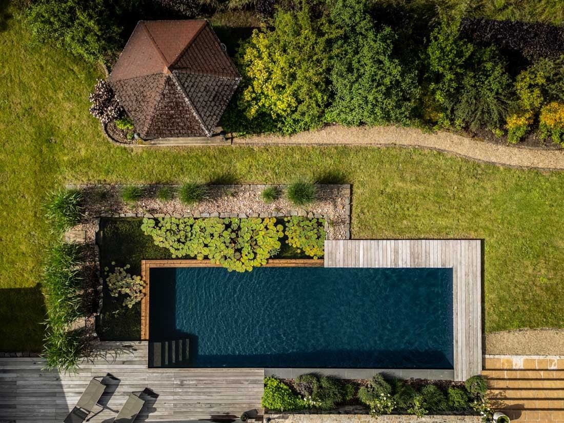 Zwemvijver met houten vlonder in een ruime tuin